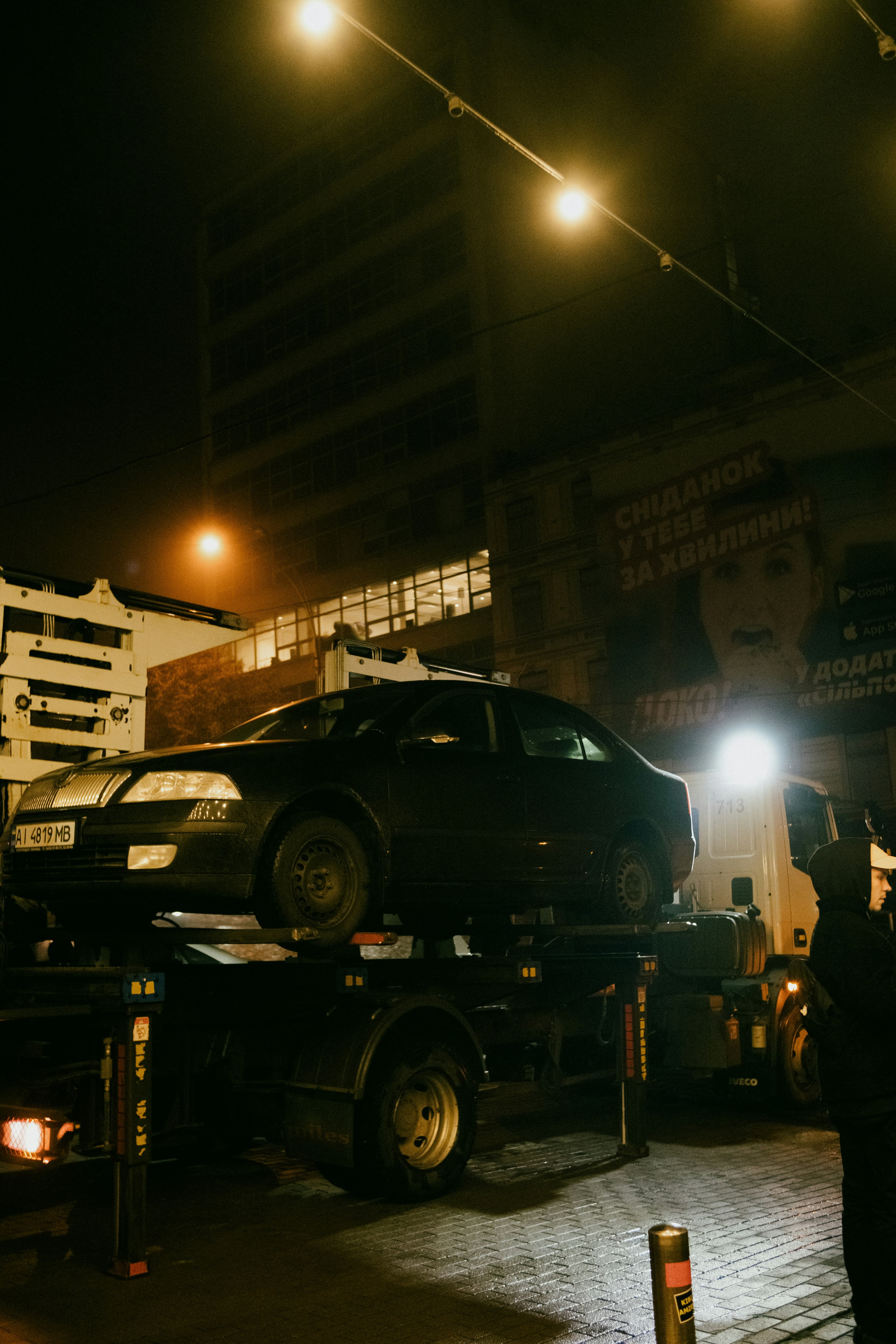 Car loaded onto a flatbed recovery truck at night