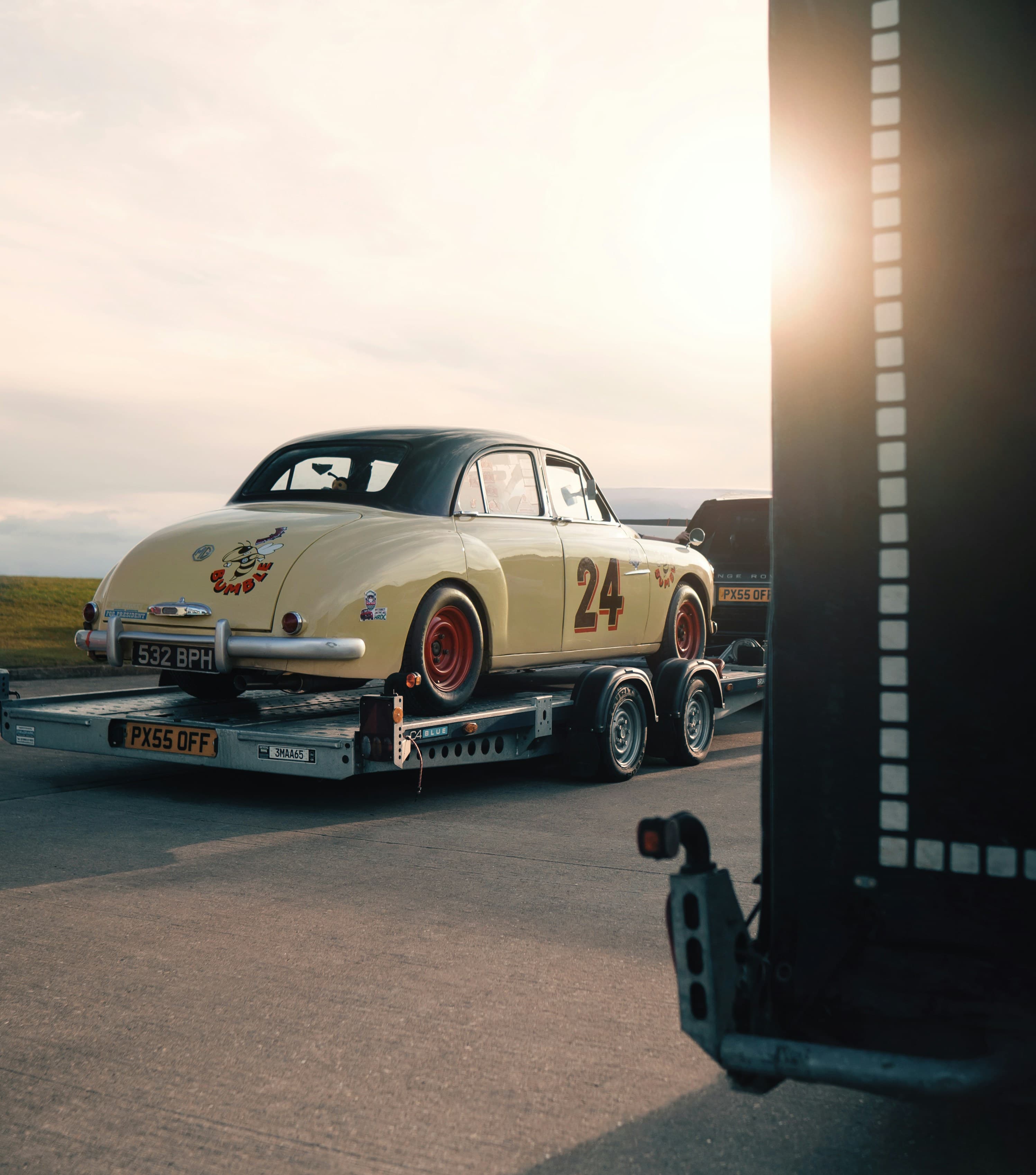 Classic car strapped onto a trailer at sunset