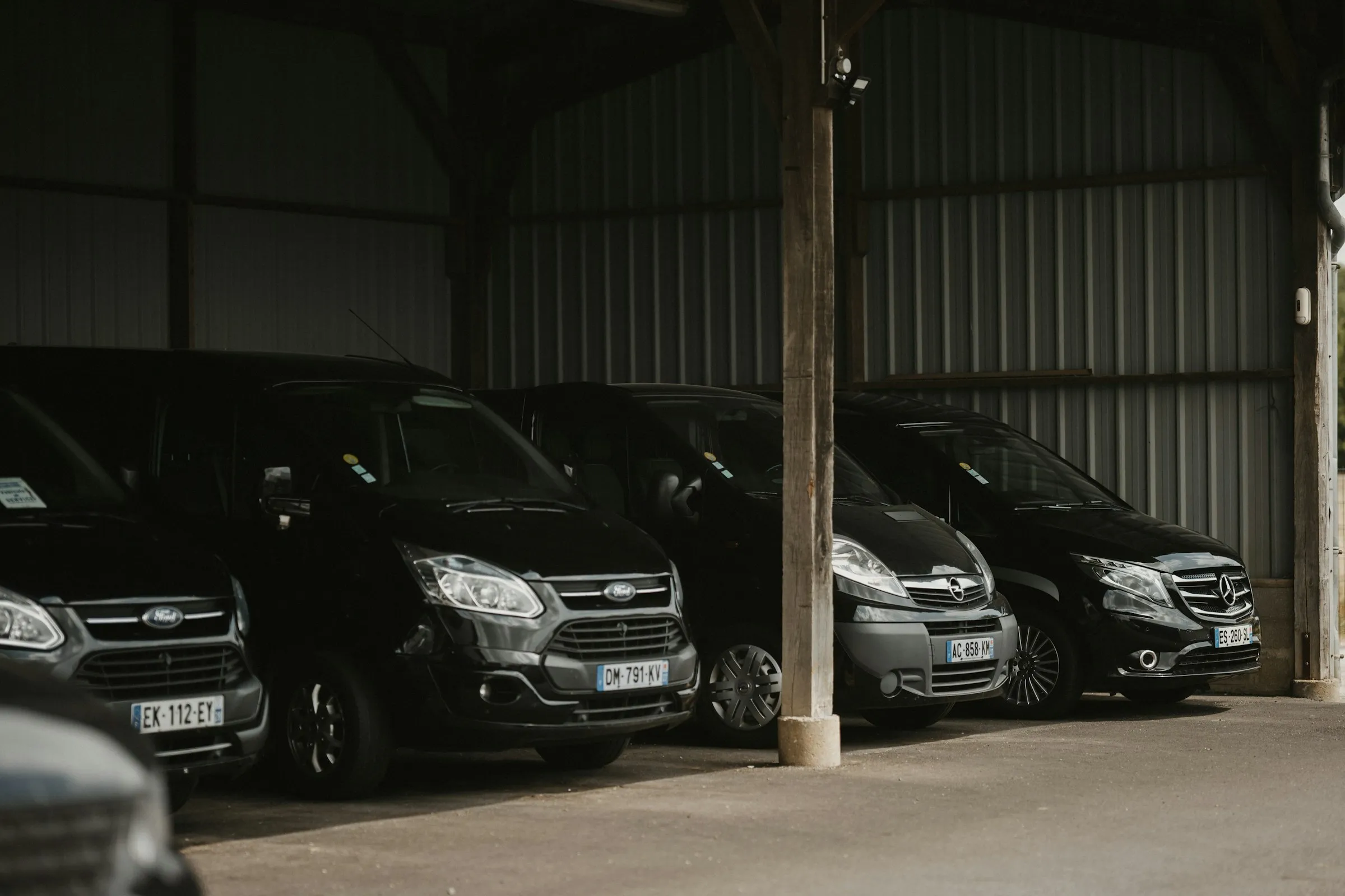Row of black vans parked under a covered bay